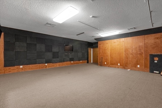 basement with carpet flooring, wooden walls, and a textured ceiling