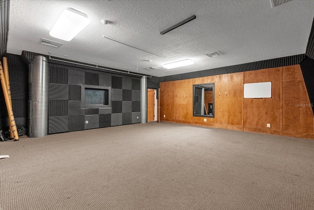 basement featuring wooden walls, carpet, and a textured ceiling