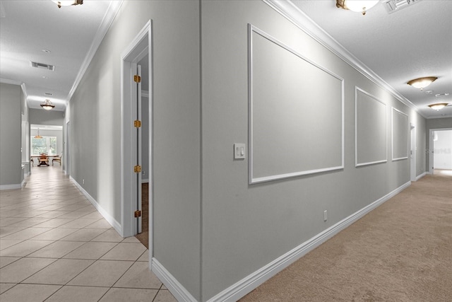 hall featuring a textured ceiling, light carpet, and ornamental molding