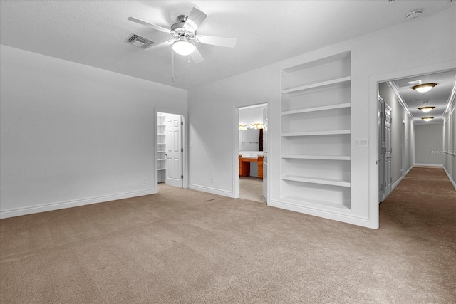 carpeted empty room featuring a textured ceiling, ceiling fan, and built in features