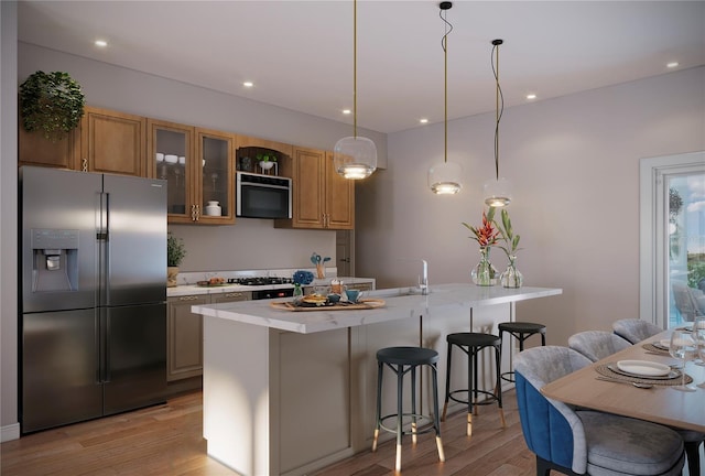 kitchen with light hardwood / wood-style flooring, a kitchen island, stainless steel appliances, decorative light fixtures, and a breakfast bar