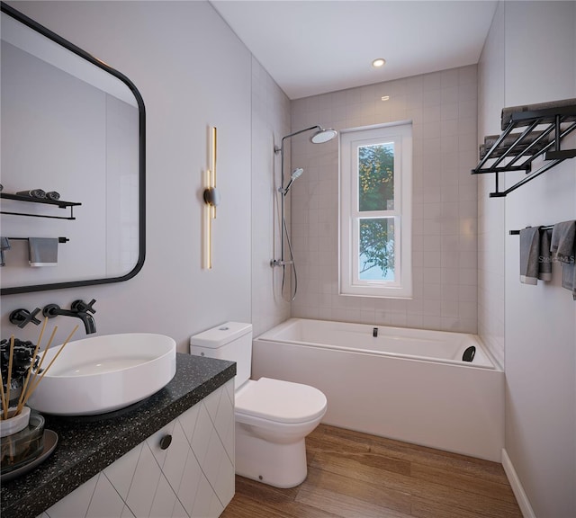 full bathroom with tiled shower / bath, vanity, hardwood / wood-style floors, and toilet