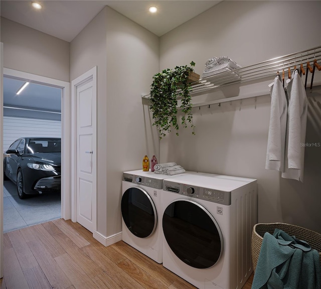 laundry room featuring washing machine and dryer and light hardwood / wood-style floors