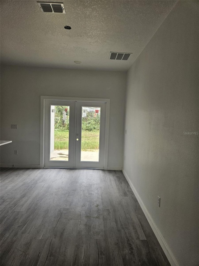 spare room featuring french doors, hardwood / wood-style flooring, and a textured ceiling