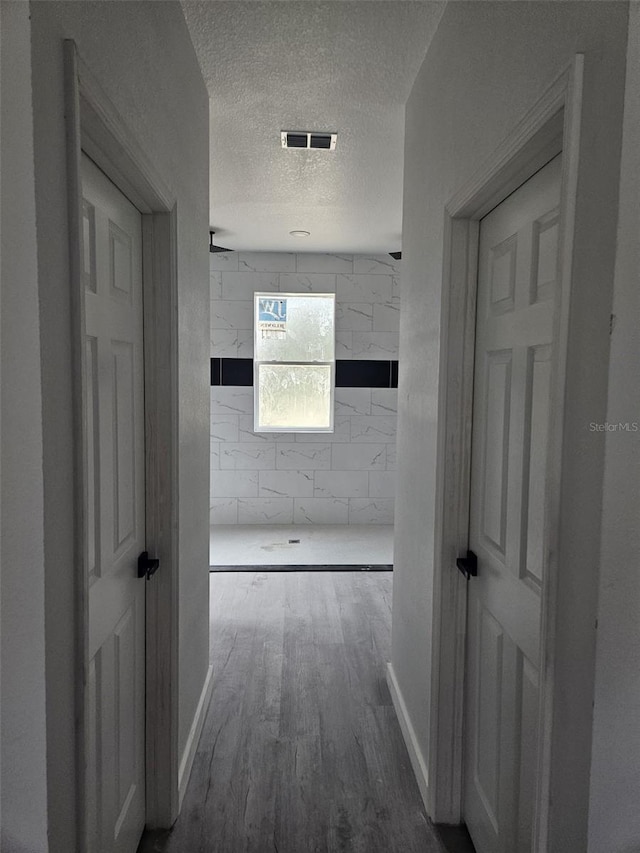 corridor with a textured ceiling and hardwood / wood-style flooring