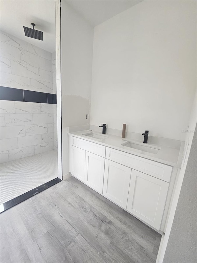 bathroom featuring vanity, wood-type flooring, and tiled shower