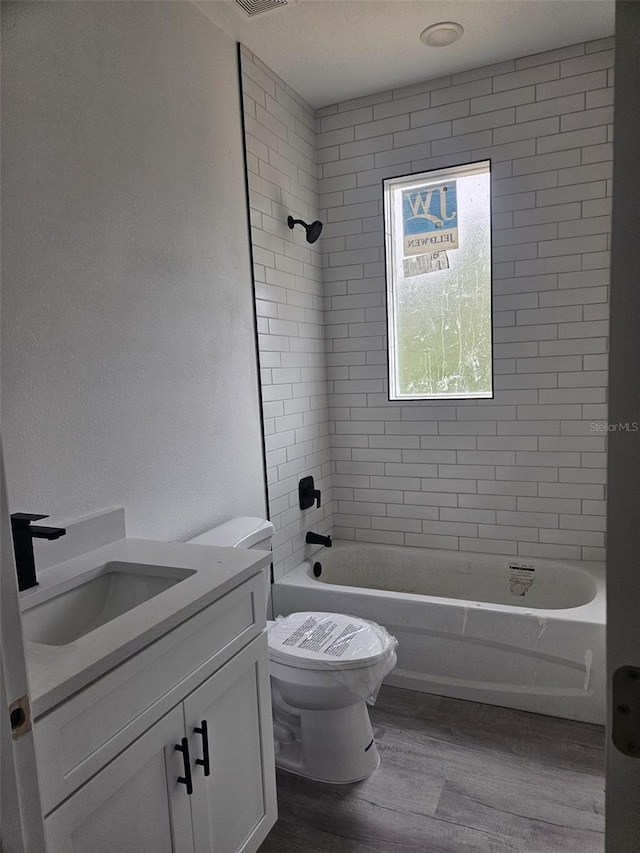 full bathroom featuring vanity, toilet, wood-type flooring, and tiled shower / bath