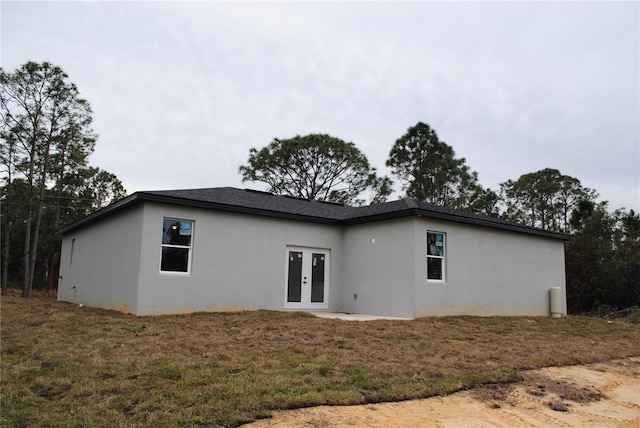 view of home's exterior featuring stucco siding, a lawn, and french doors