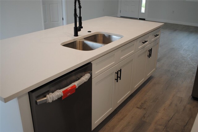 kitchen with dark wood finished floors, light countertops, white cabinets, a sink, and dishwasher