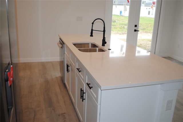 kitchen with white cabinetry, a sink, an island with sink, wood finished floors, and dishwasher