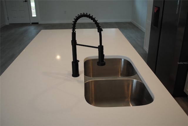 room details with light countertops, a sink, baseboards, and wood finished floors