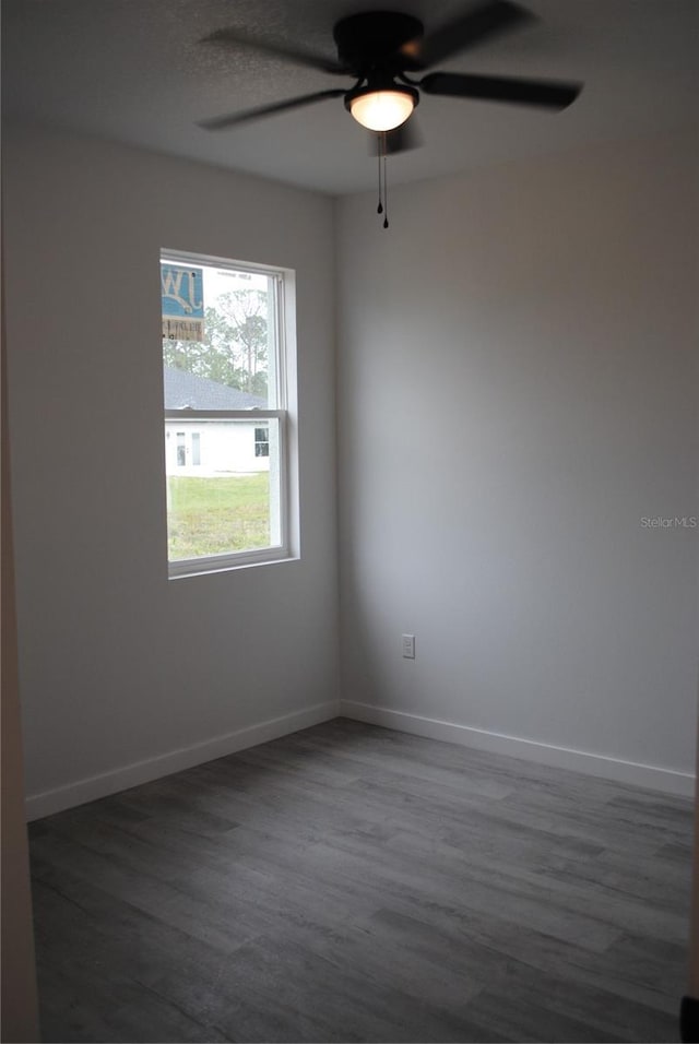 empty room featuring dark wood-style floors, ceiling fan, and baseboards