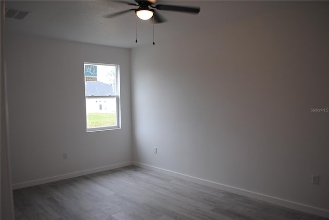 spare room featuring visible vents, baseboards, and wood finished floors