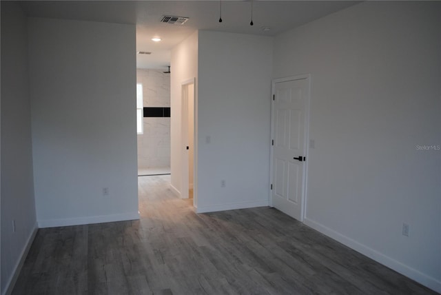 spare room with wood finished floors, visible vents, and baseboards