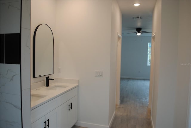 bathroom with wood finished floors, a sink, visible vents, baseboards, and double vanity