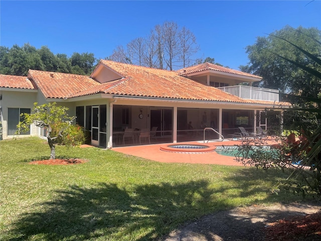 back of property featuring a patio area, a swimming pool with hot tub, a balcony, and a lawn