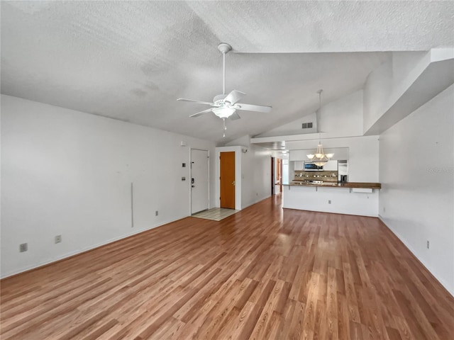 unfurnished living room with ceiling fan with notable chandelier, light hardwood / wood-style floors, high vaulted ceiling, and a textured ceiling