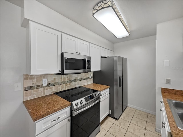 kitchen with appliances with stainless steel finishes, backsplash, white cabinetry, sink, and light tile floors