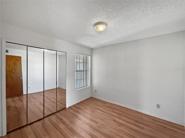 unfurnished bedroom featuring a closet, light hardwood / wood-style flooring, and a textured ceiling