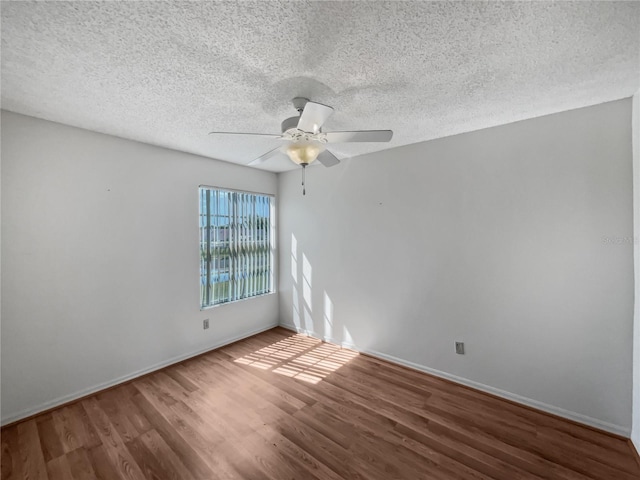 empty room with dark hardwood / wood-style flooring, ceiling fan, and a textured ceiling