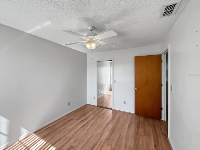 empty room featuring light hardwood / wood-style floors, ceiling fan, and a textured ceiling