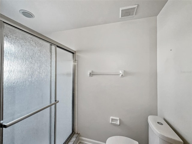 bathroom featuring a shower with shower door and toilet