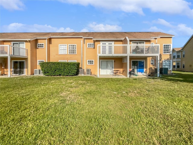 rear view of property with a patio, a yard, central AC, and a balcony