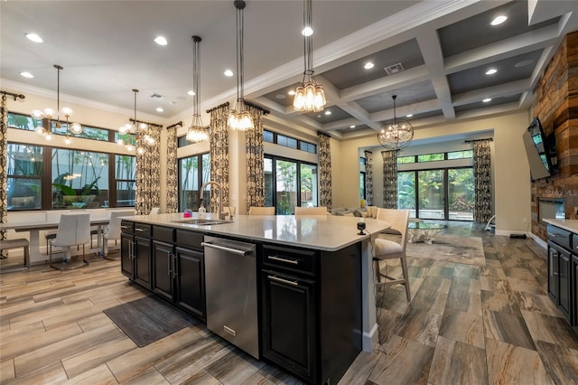 kitchen with coffered ceiling, pendant lighting, stainless steel dishwasher, and an island with sink