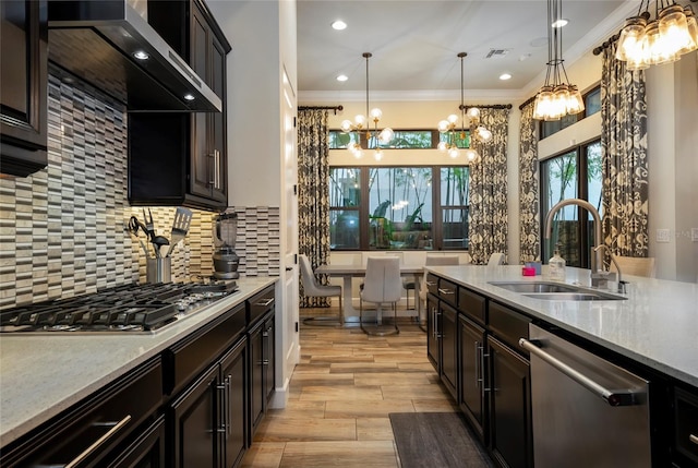 kitchen with wall chimney exhaust hood, sink, backsplash, stainless steel appliances, and pendant lighting