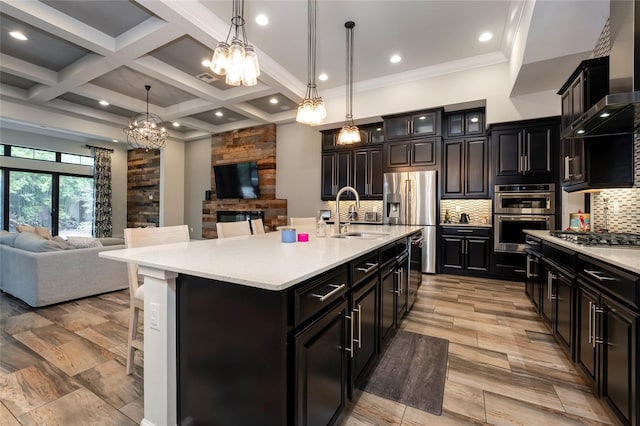 kitchen with coffered ceiling, sink, backsplash, wall chimney range hood, and pendant lighting