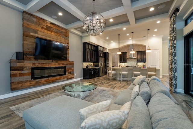 living room with beamed ceiling, a fireplace, light hardwood / wood-style flooring, an inviting chandelier, and coffered ceiling