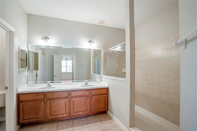 bathroom featuring a tile shower, vanity with extensive cabinet space, double sink, and tile flooring