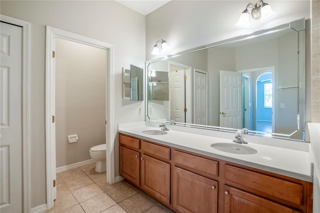 bathroom featuring large vanity, toilet, double sink, and tile flooring