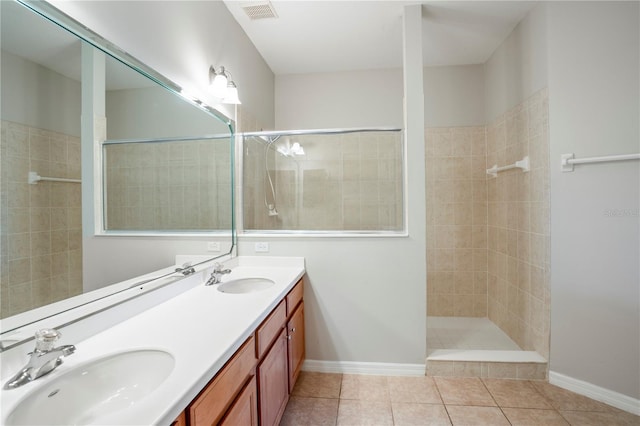 bathroom featuring large vanity, tiled shower, double sink, and tile flooring