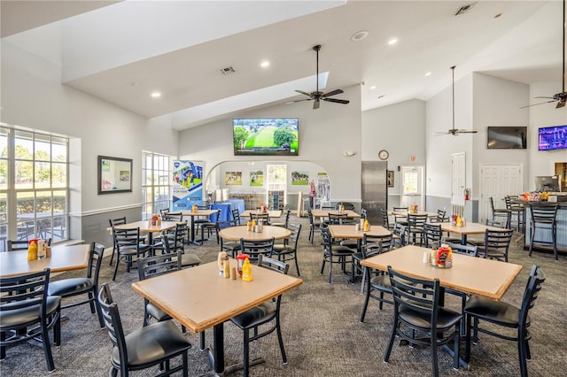 carpeted dining space with high vaulted ceiling and ceiling fan