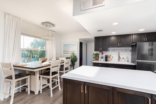 kitchen featuring light hardwood / wood-style flooring, stainless steel fridge, sink, backsplash, and dark brown cabinetry