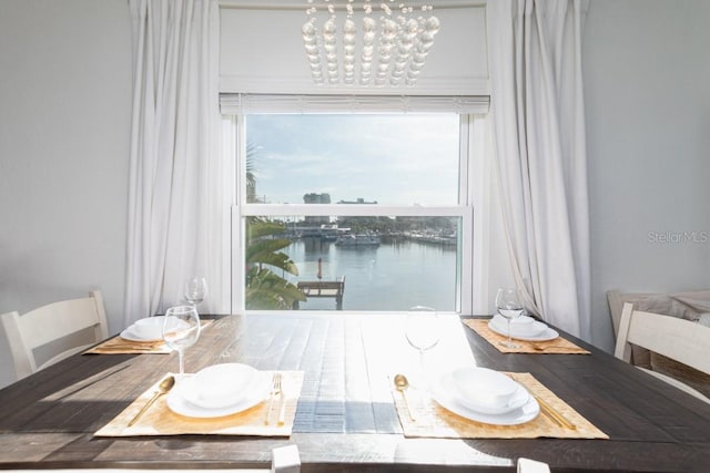 dining room featuring a notable chandelier and a water view