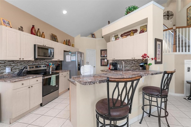 kitchen featuring backsplash, a kitchen breakfast bar, stainless steel appliances, and light tile flooring