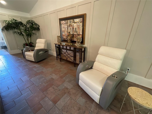 living area featuring lofted ceiling and dark tile flooring