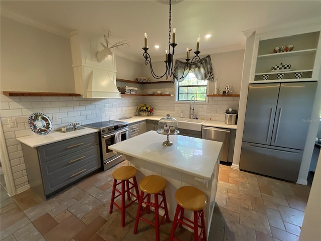 kitchen featuring light tile floors, premium appliances, tasteful backsplash, crown molding, and a kitchen breakfast bar