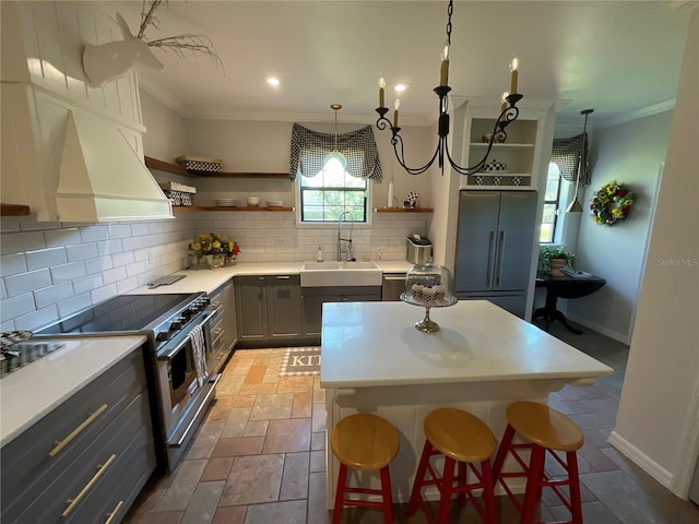 kitchen with gray cabinetry, backsplash, sink, a breakfast bar area, and high quality appliances