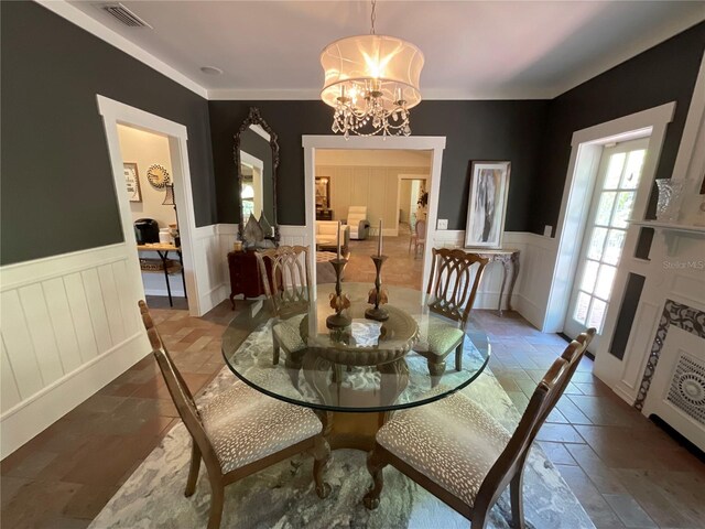 tiled dining room with a chandelier and crown molding