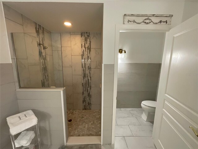 bathroom featuring toilet, tile floors, and tiled shower