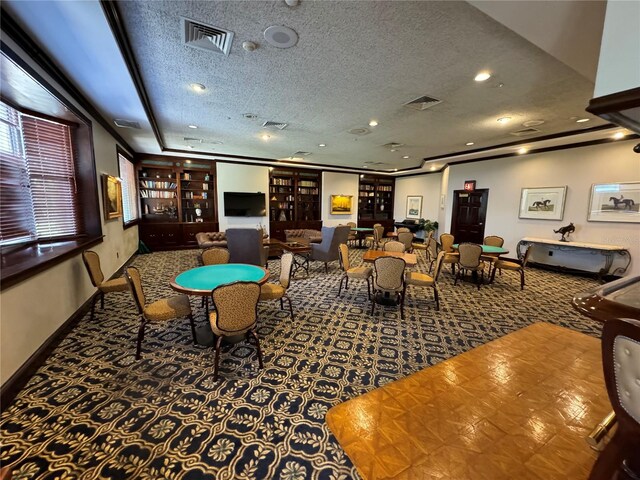 game room with a textured ceiling, dark carpet, and crown molding