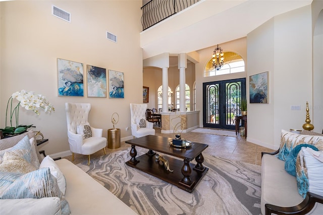 tiled living room featuring french doors, an inviting chandelier, decorative columns, and a high ceiling