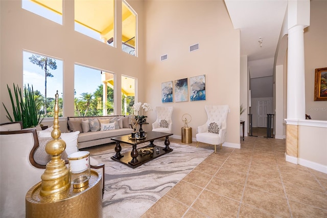 tiled living room featuring decorative columns and a towering ceiling