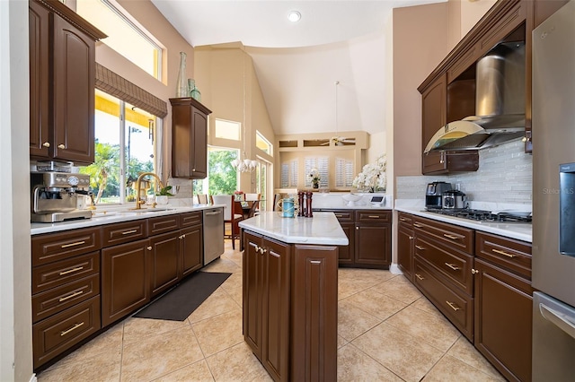 kitchen featuring stainless steel appliances, light tile flooring, tasteful backsplash, wall chimney exhaust hood, and a center island