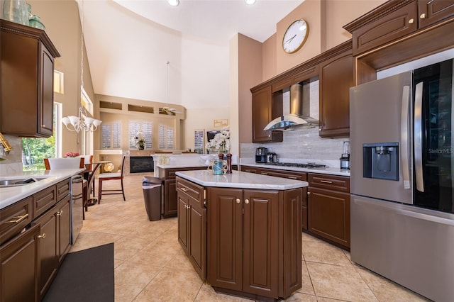 kitchen with a center island, wall chimney exhaust hood, backsplash, stainless steel appliances, and pendant lighting