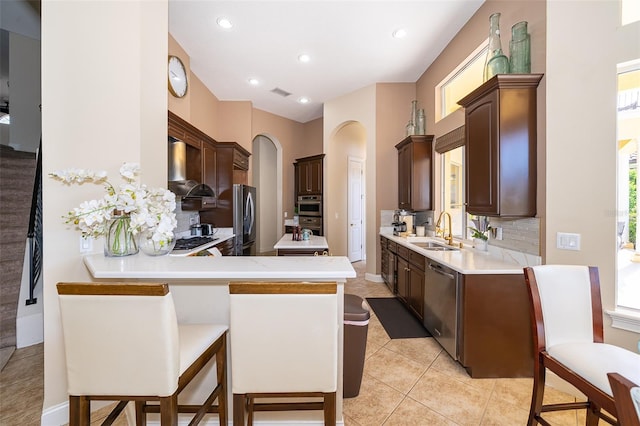 kitchen featuring light tile floors, sink, wall chimney range hood, tasteful backsplash, and stainless steel appliances