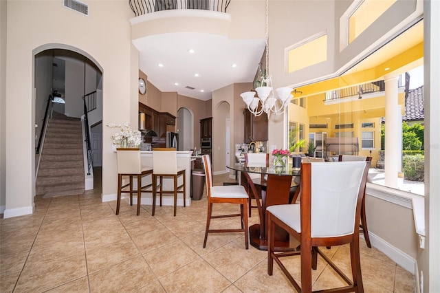 tiled dining area with a towering ceiling and a chandelier